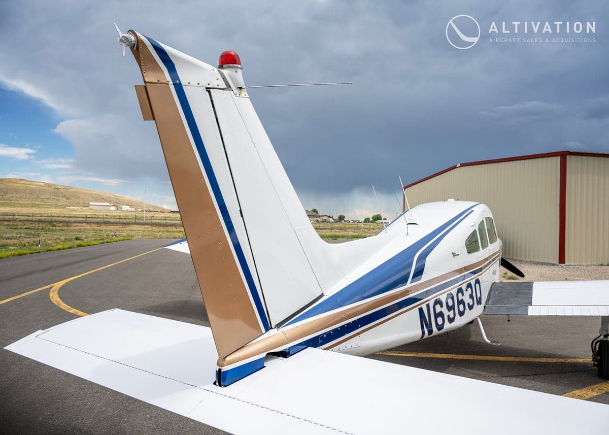 Rear view of a white and blue Piper aircraft showing the tail and registration number.