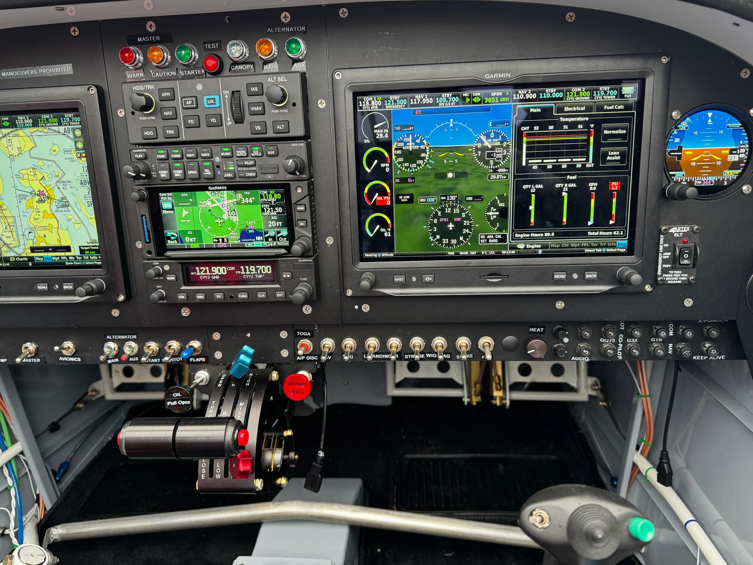 A detailed view of the aircraft's central instrument panel and throttle quadrant, showing multiple Garmin displays and various switches.