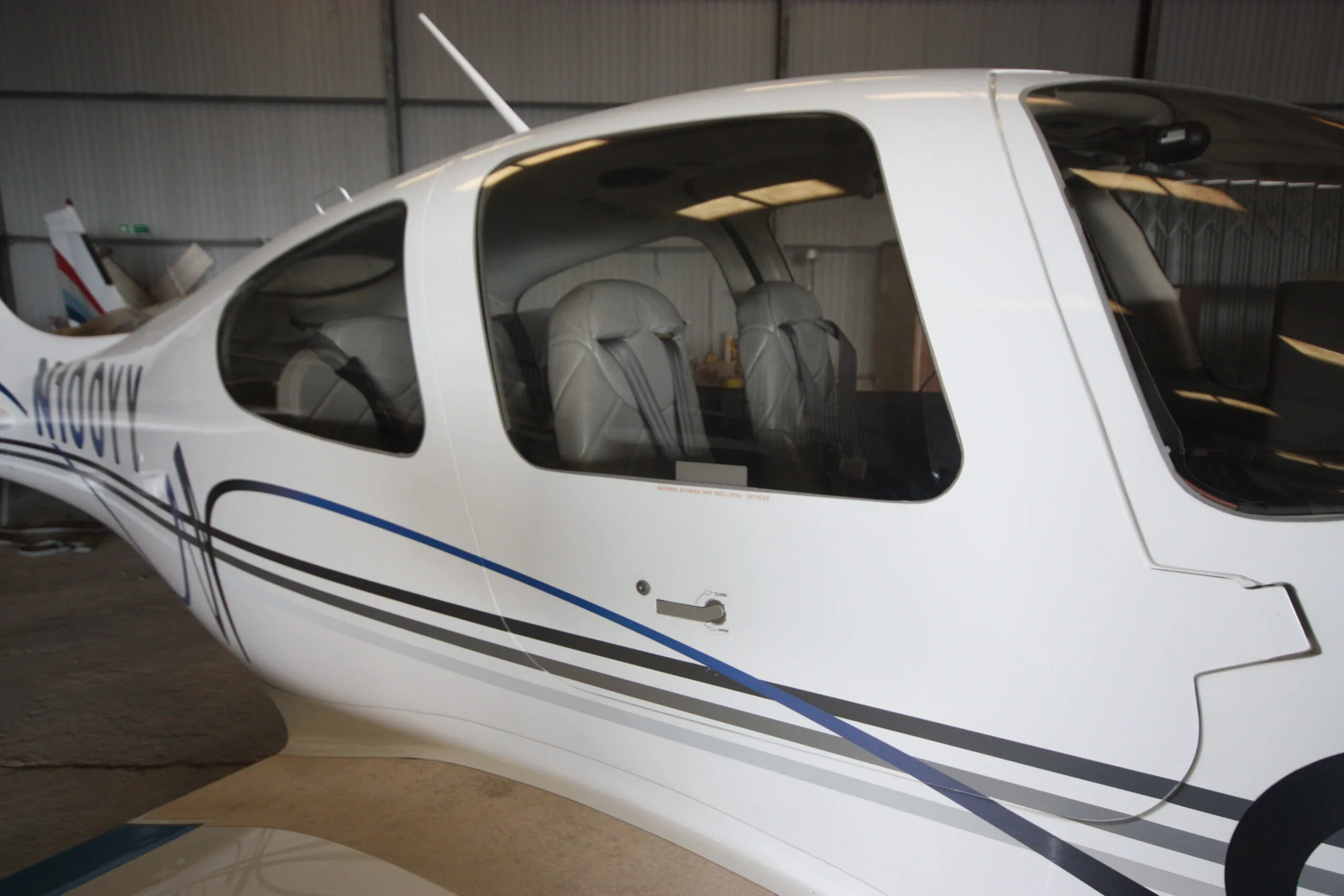 A close-up side view of the white Cirrus SR22 aircraft showing its windows and light grey interior seats.