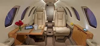 The interior of an aircraft with leather seats and a table.