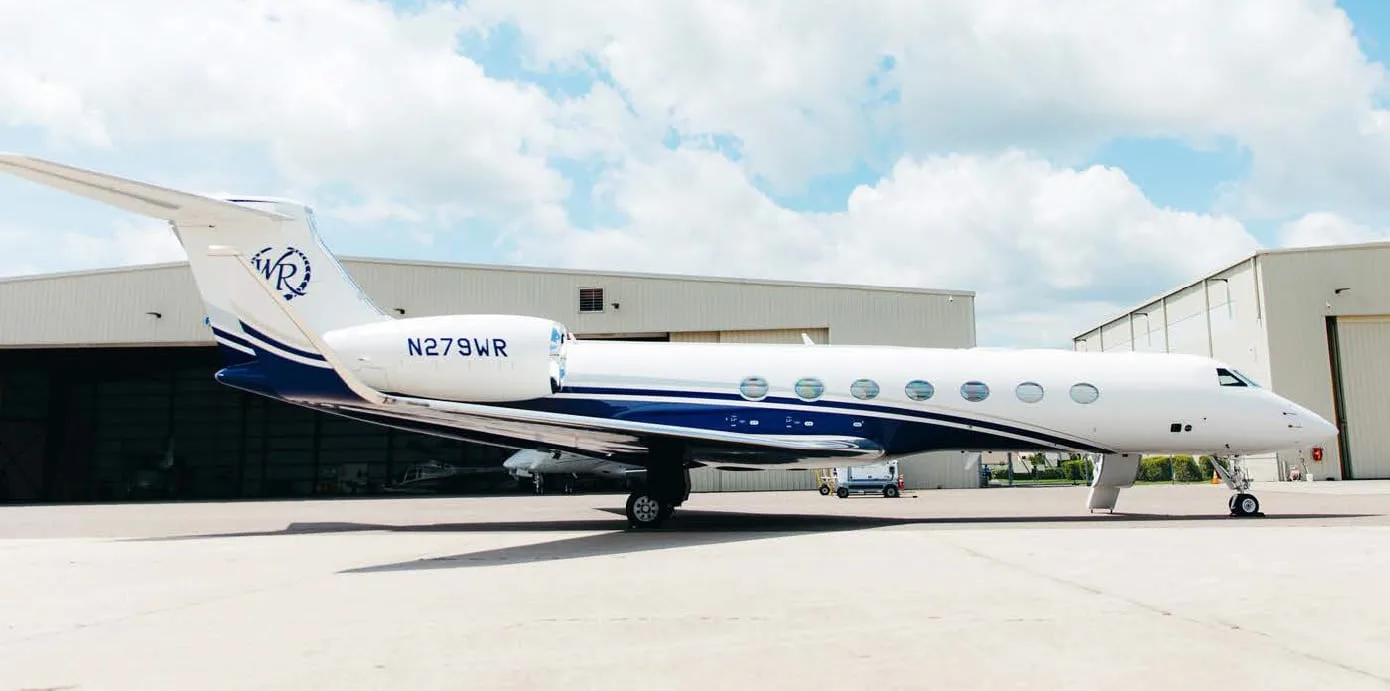 A side view of the white and blue Gulfstream G550 business jet, registration N279WR, parked on an airfield.