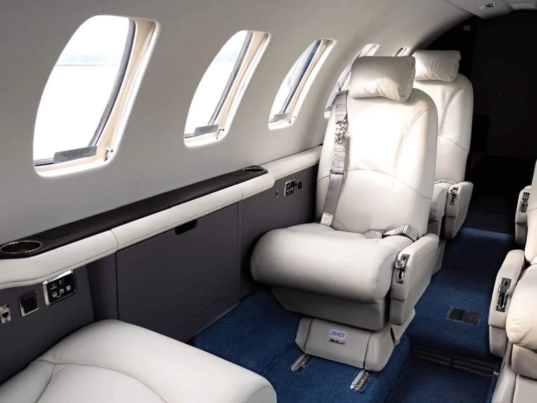 Aircraft interior with white leather seats and side console.