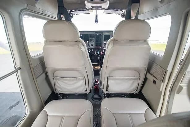 View from the rear cabin of a small aircraft looking forward at the two front seats and the cockpit beyond.