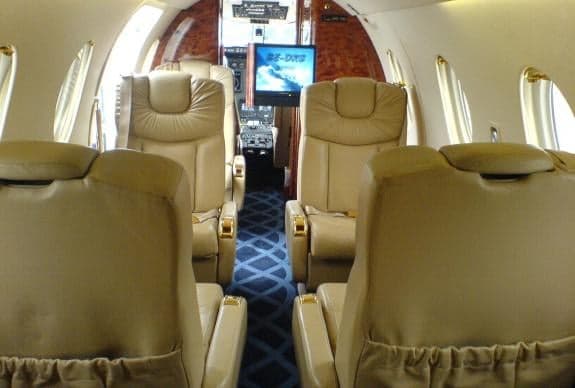 View of the aircraft cabin with tan leather seats and wood trim.