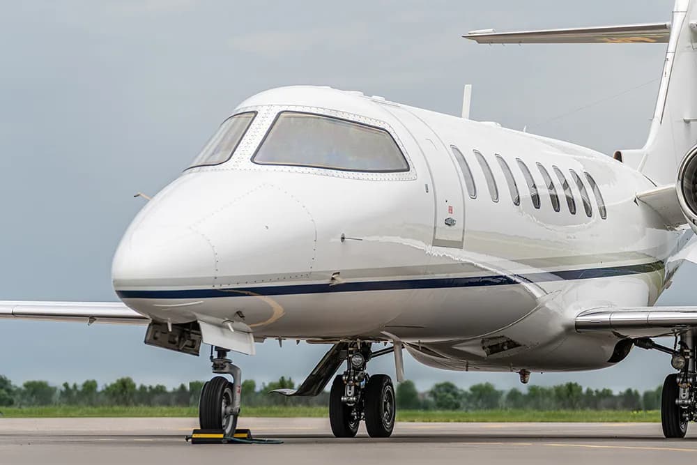 A close-up front-side view of a white Cessna Citation business jet's nose and cockpit.