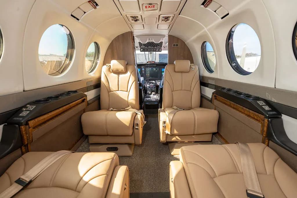 Interior view of the aircraft cabin with tan leather seats, looking forward towards the cockpit.