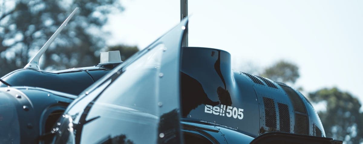 Close-up of a dark blue Bell 505 helicopter with the door open.