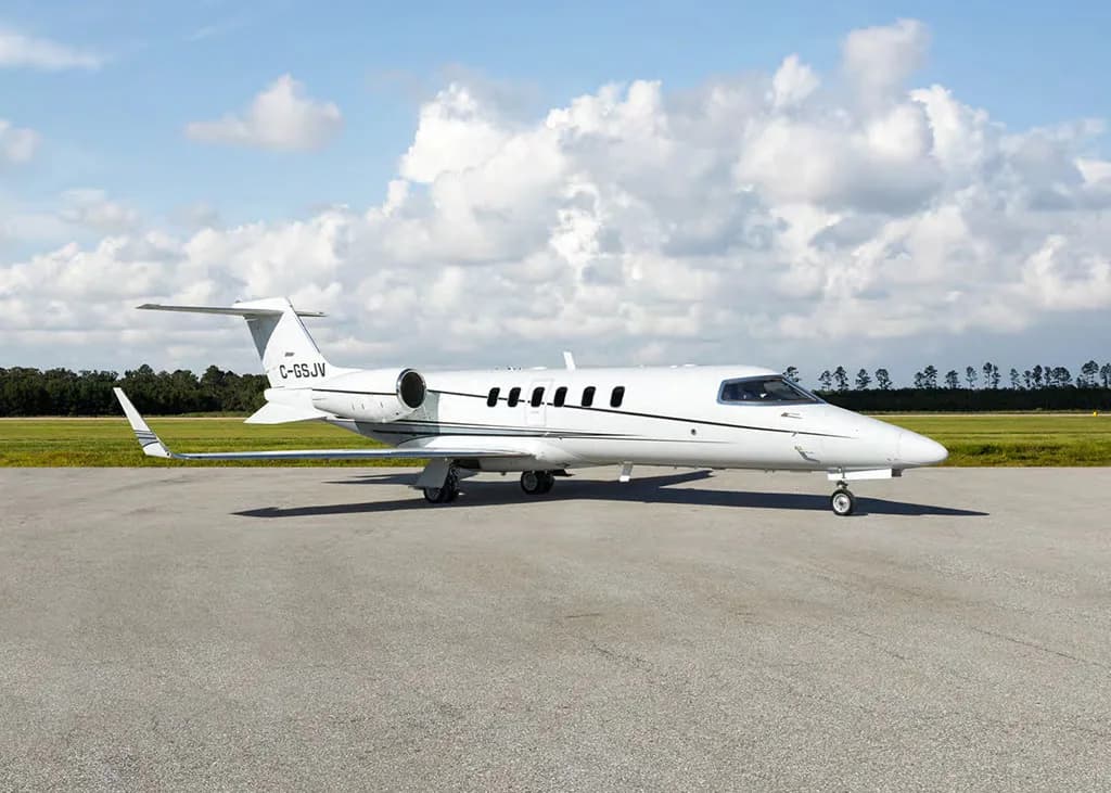 A white Learjet 75 business jet with a black stripe, registration C-GSJV, viewed from a slightly different angle on a tarmac.