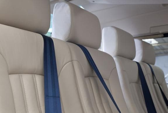 Close-up of the cream-colored leather seats with blue seatbelts in the helicopter cabin.