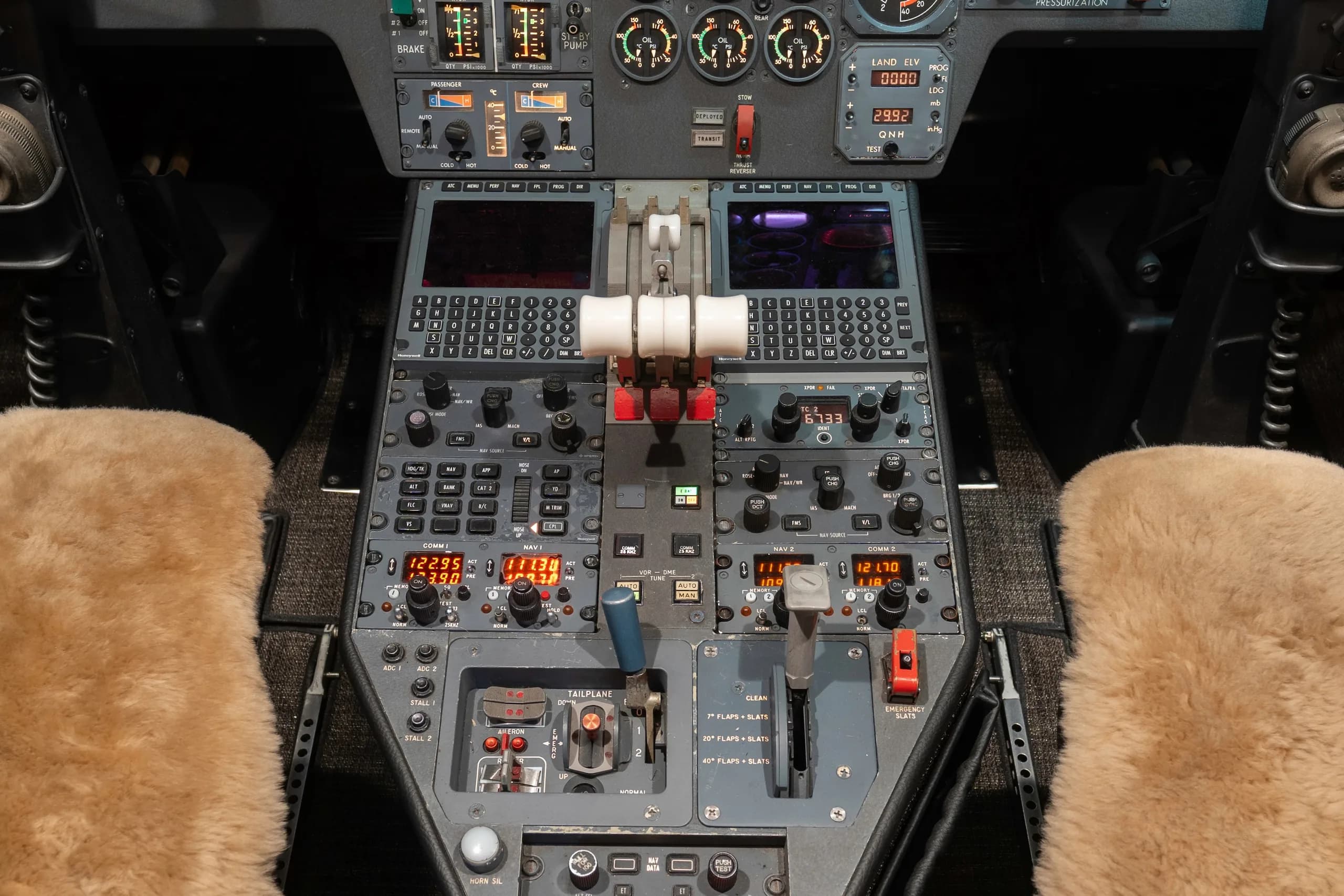 An overhead view of a business jet's cockpit center console with throttles, controls, and displays.