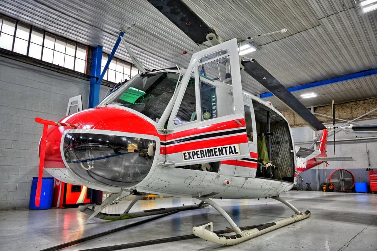 Side view of the N857SD helicopter with open doors in a hangar.