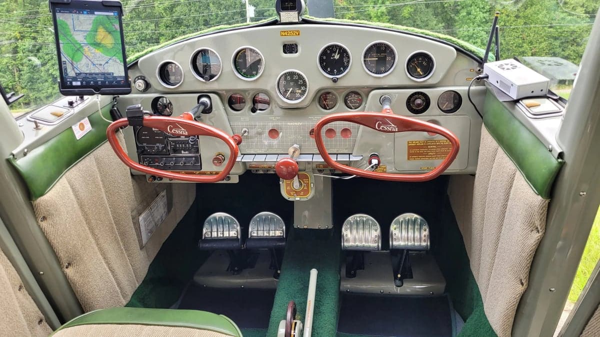 The cockpit of a Cessna 170 features a classic instrument panel and red yokes.
