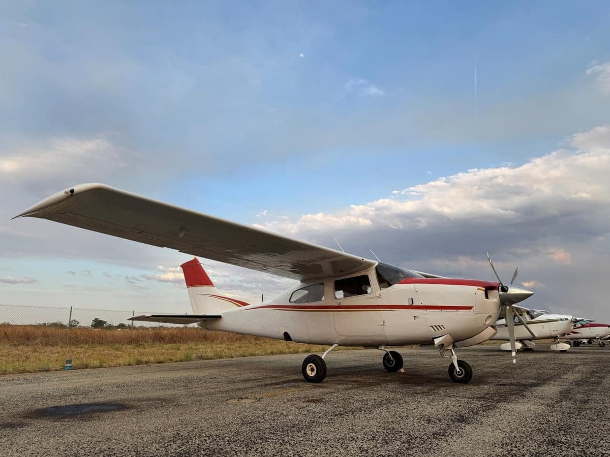 A Cessna 210 Centurion aircraft parked on the tarmac under a cloudy sky.