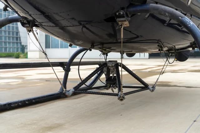 A close-up view of the underside and landing skids of a dark blue helicopter.