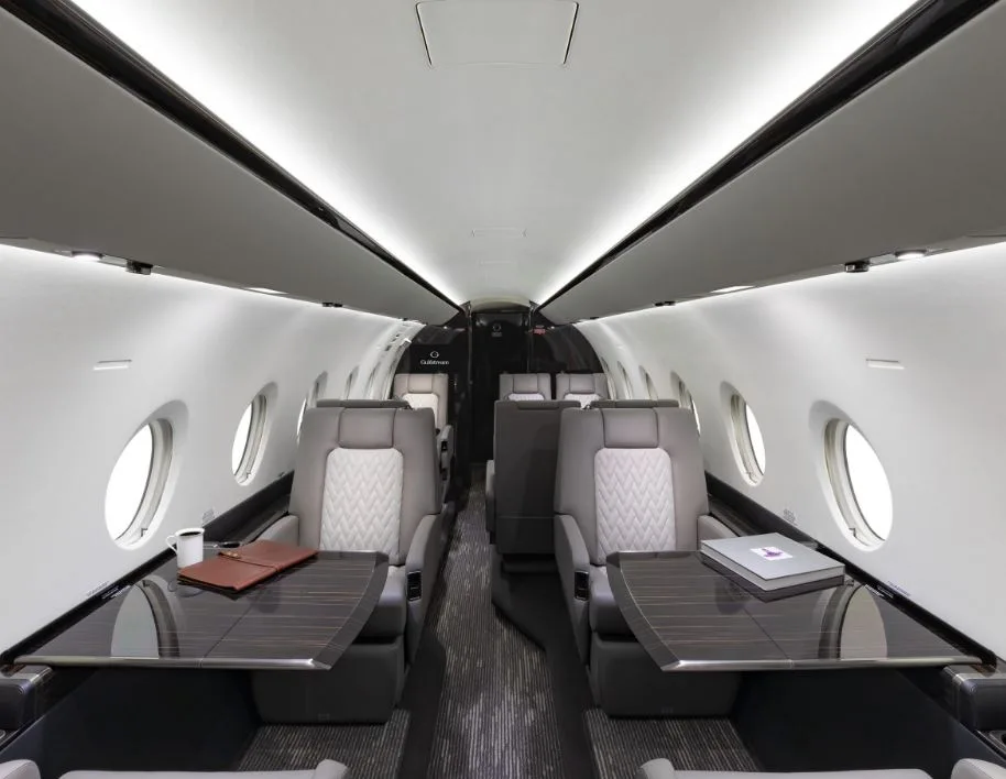 View of the aircraft cabin with leather seats and dark wood accents.