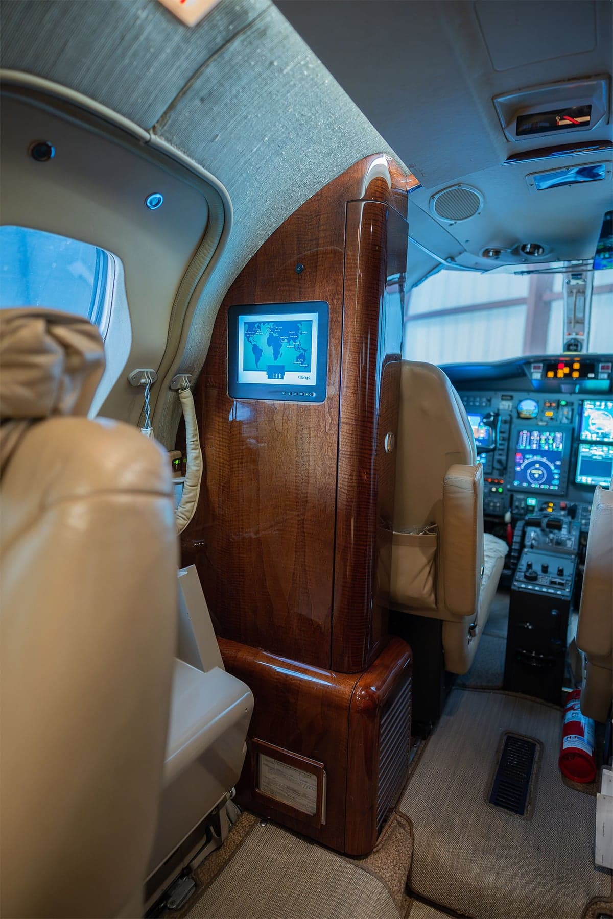 View of the aircraft interior showing a wooden cabinet with a monitor and the cockpit.