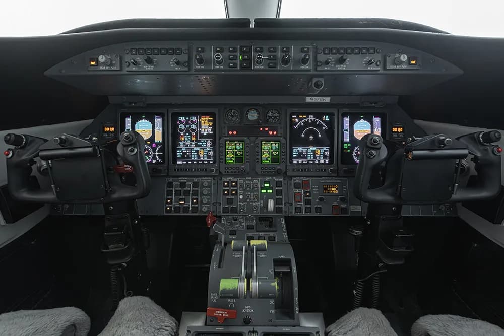 The cockpit of a private jet with multiple digital displays and control panels.