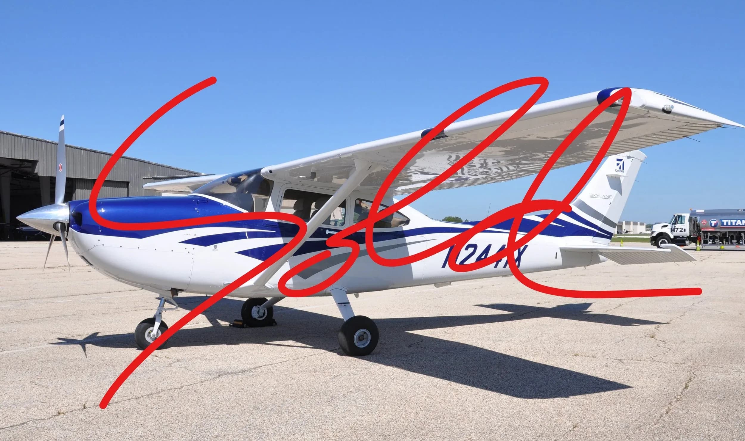 A white and blue Cessna 182 Skylane (N241X) parked on an airfield under a clear blue sky.