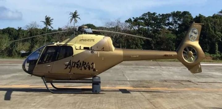 Side view of a gold helicopter on the tarmac.