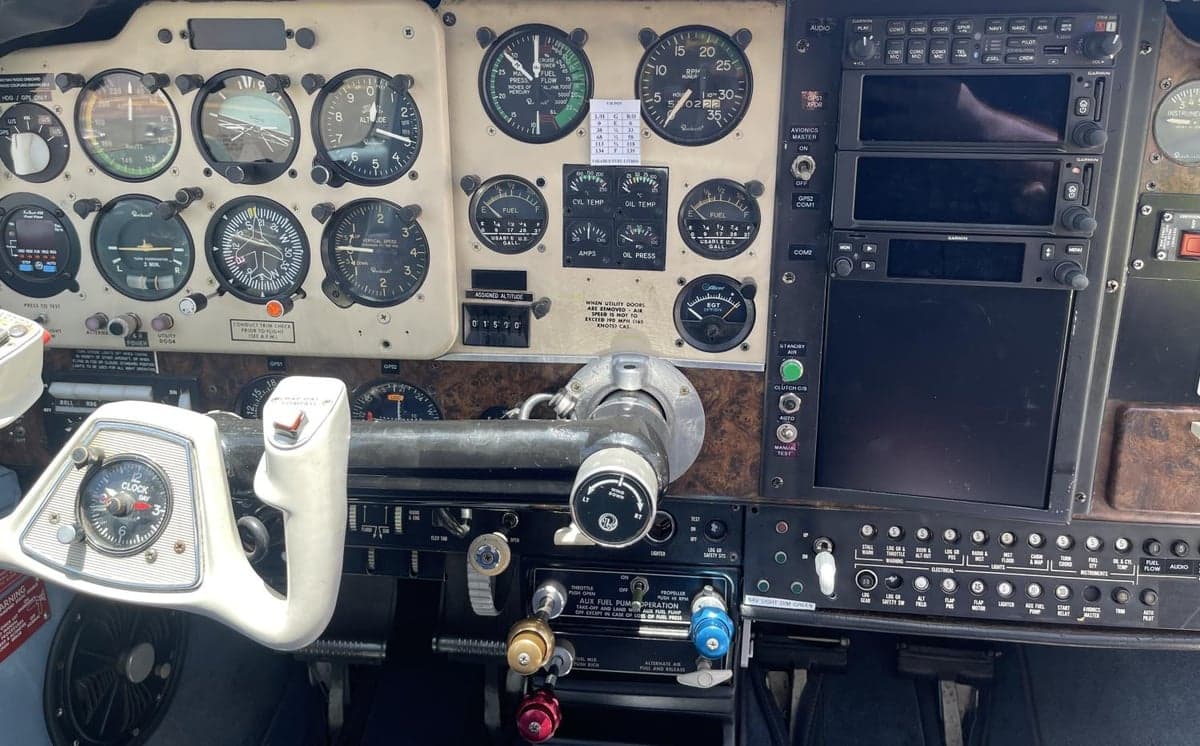 A close-up view of a light aircraft's instrument panel, showing gauges, avionics, and the control yoke.
