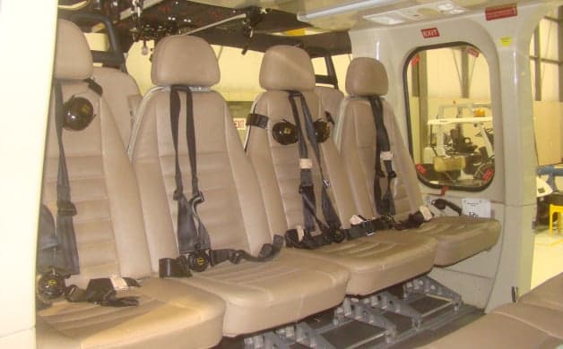 The interior of the helicopter features tan leather seats with black seatbelts.