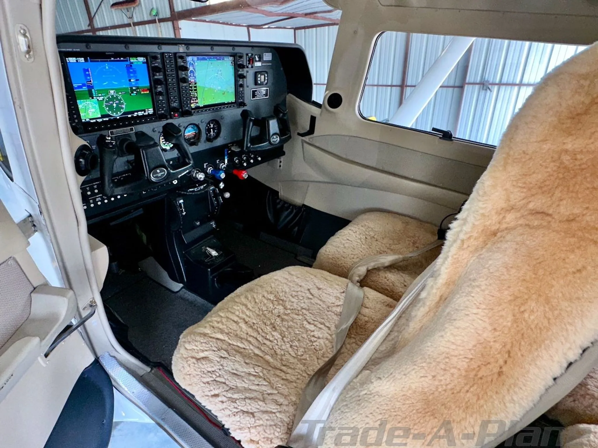 View of the cockpit of a Cessna Stationair HD with sheepskin seat covers and modern avionics.