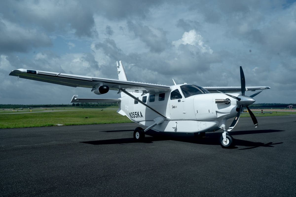 A white Quest Kodiak 100 aircraft, registration N355KA, parked on an asphalt tarmac under a cloudy sky.
