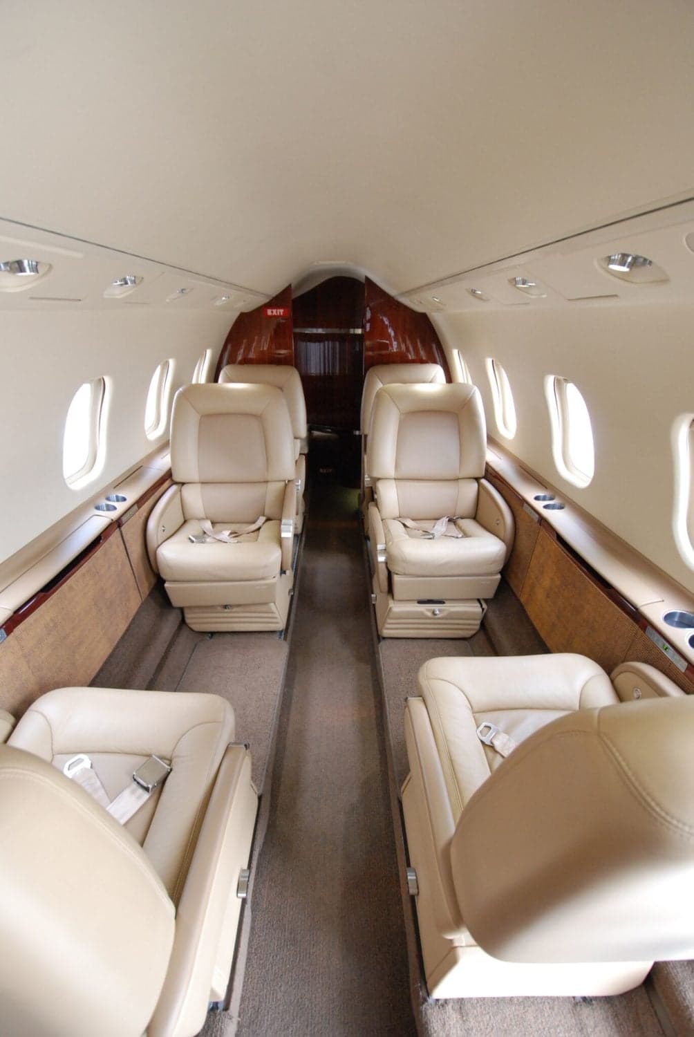 The interior cabin of a business jet, featuring beige leather seats arranged in a club configuration.