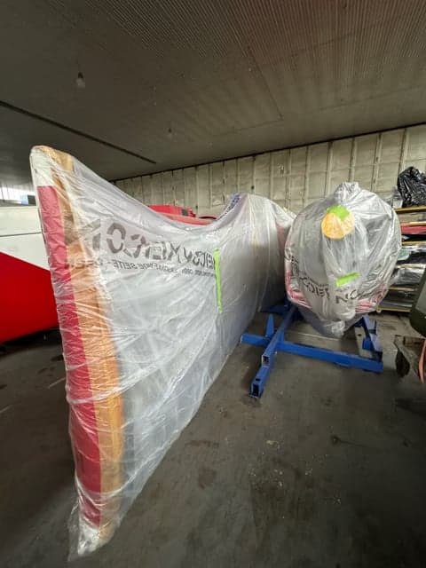 Aircraft parts wrapped in plastic in a hangar.