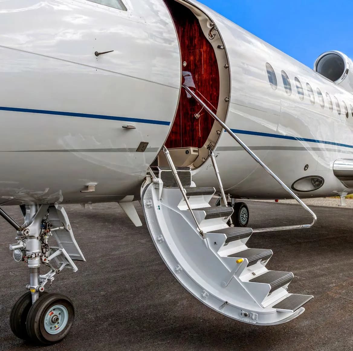 A close-up of the extended airstairs and open entry door of a business jet.