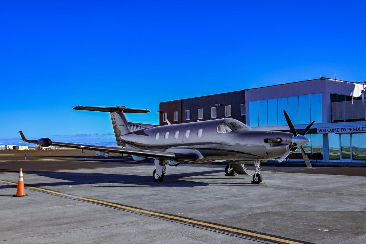 Pilatus PC-12 aircraft N111WG parked on the tarmac in front of a building.