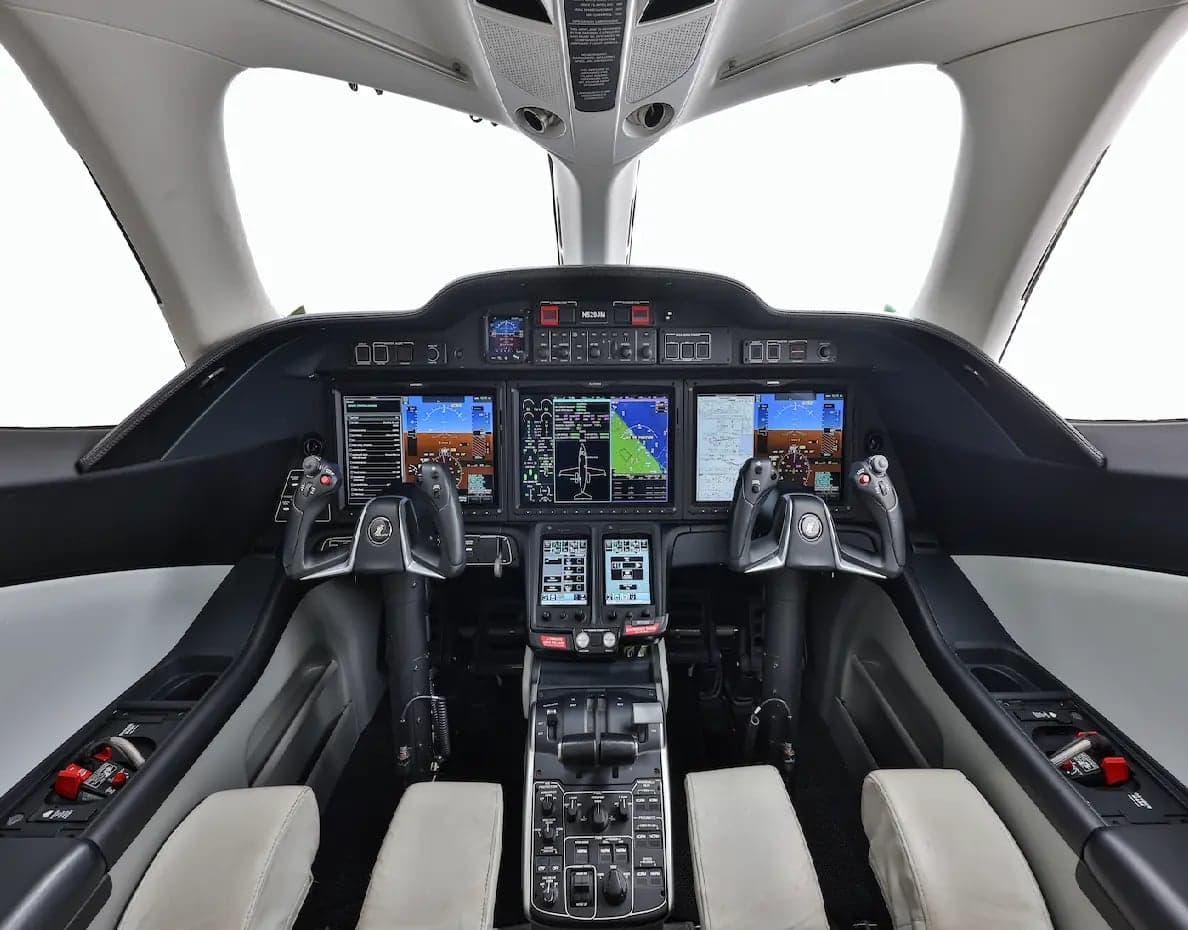 The modern cockpit of a HondaJet HA-420, featuring multiple large digital displays and control yokes.