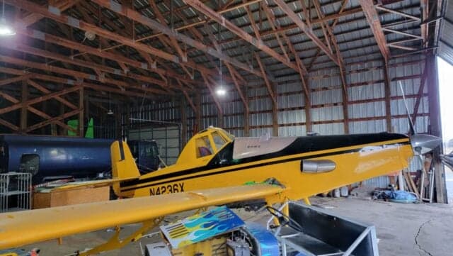 A yellow and black Air Tractor AT-400 sits inside a hangar.