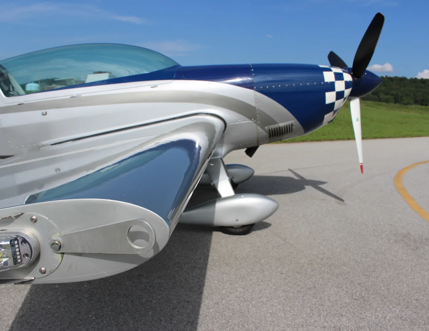 A close-up view of the blue and silver checkered nose and wing of the N51E Extra EA-300/L aircraft.