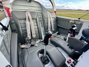 Interior view of the aircraft cabin with gray seats and seatbelts.