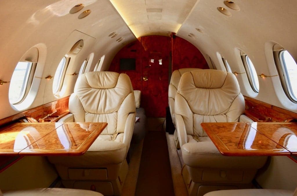 Interior of the aircraft with leather seats and wooden tables.
