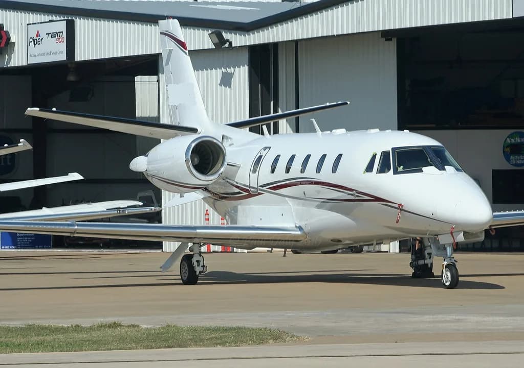 A white jet aircraft parked on the tarmac in front of a hangar.