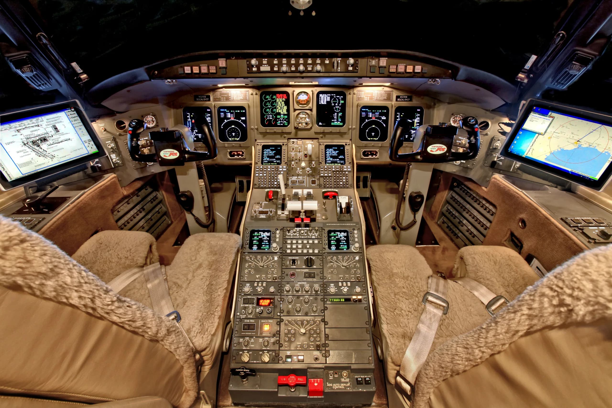 The cockpit of a business jet with multiple display screens, control panels, and sheepskin-covered seats.