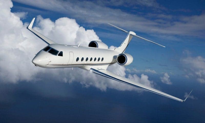A Gulfstream business jet in flight against a cloudy sky.
