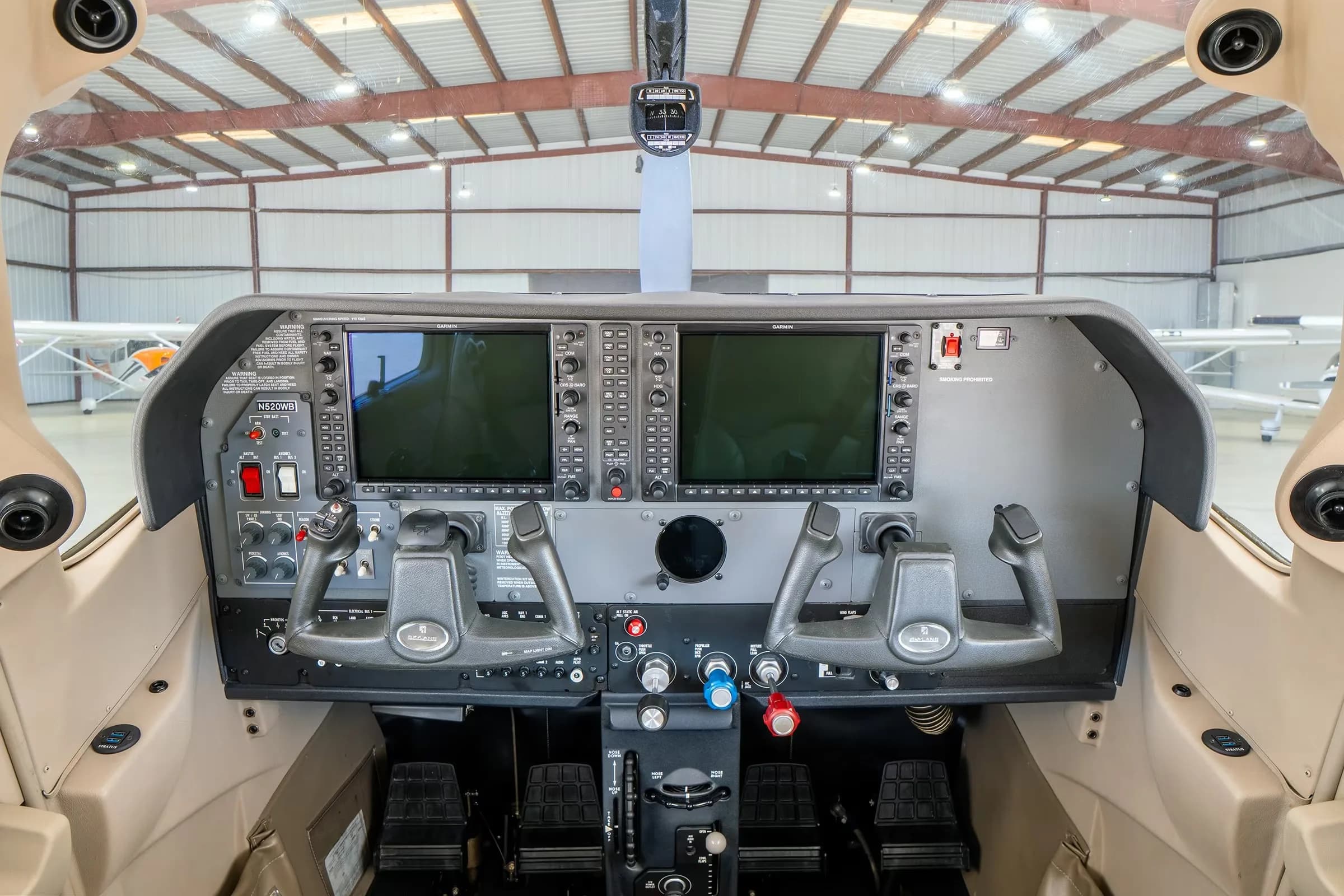The cockpit of a Cessna Skylane, showing the instrument panel with two large Garmin displays and dual yokes.