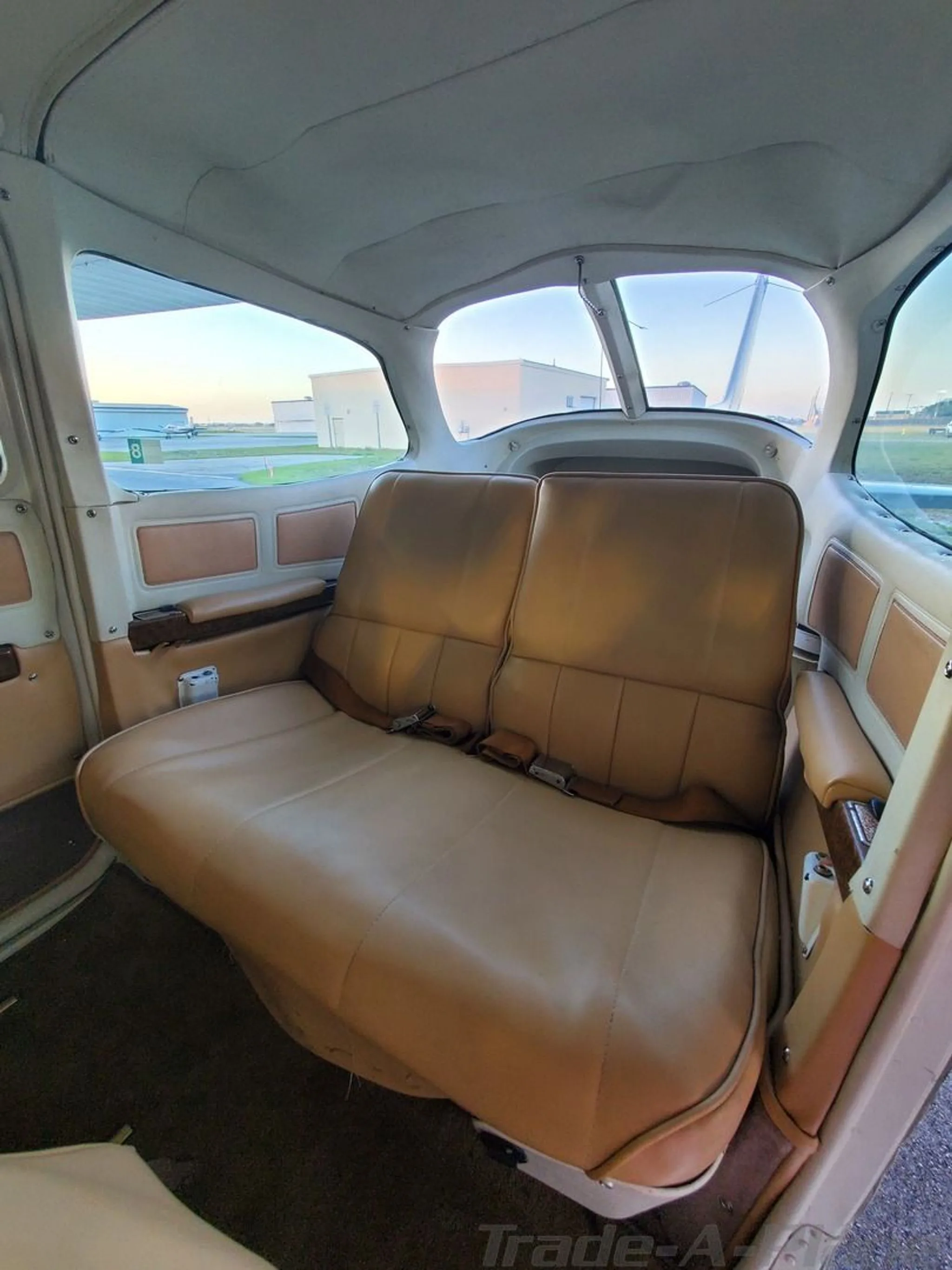 A view of the tan leather rear bench seat in the cabin of a Cessna Cutlass RG II.