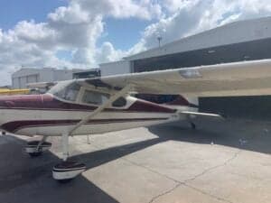 A Cessna 170A aircraft with a maroon and white paint scheme parked on the tarmac.
