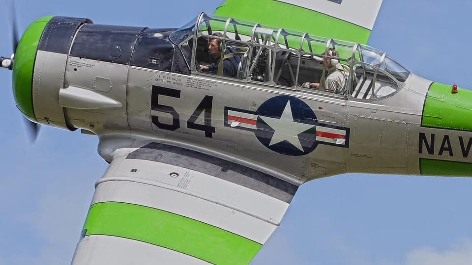 Close-up of a silver and green T-6 Texan aircraft in flight.