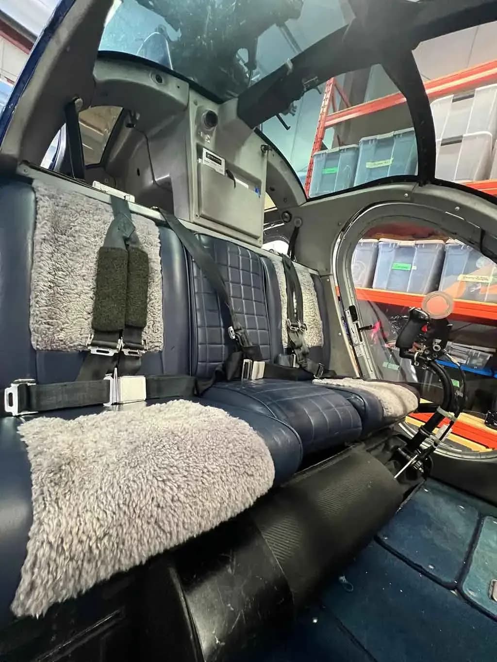 The interior of the helicopter cabin, featuring blue quilted seats with sheepskin covers.