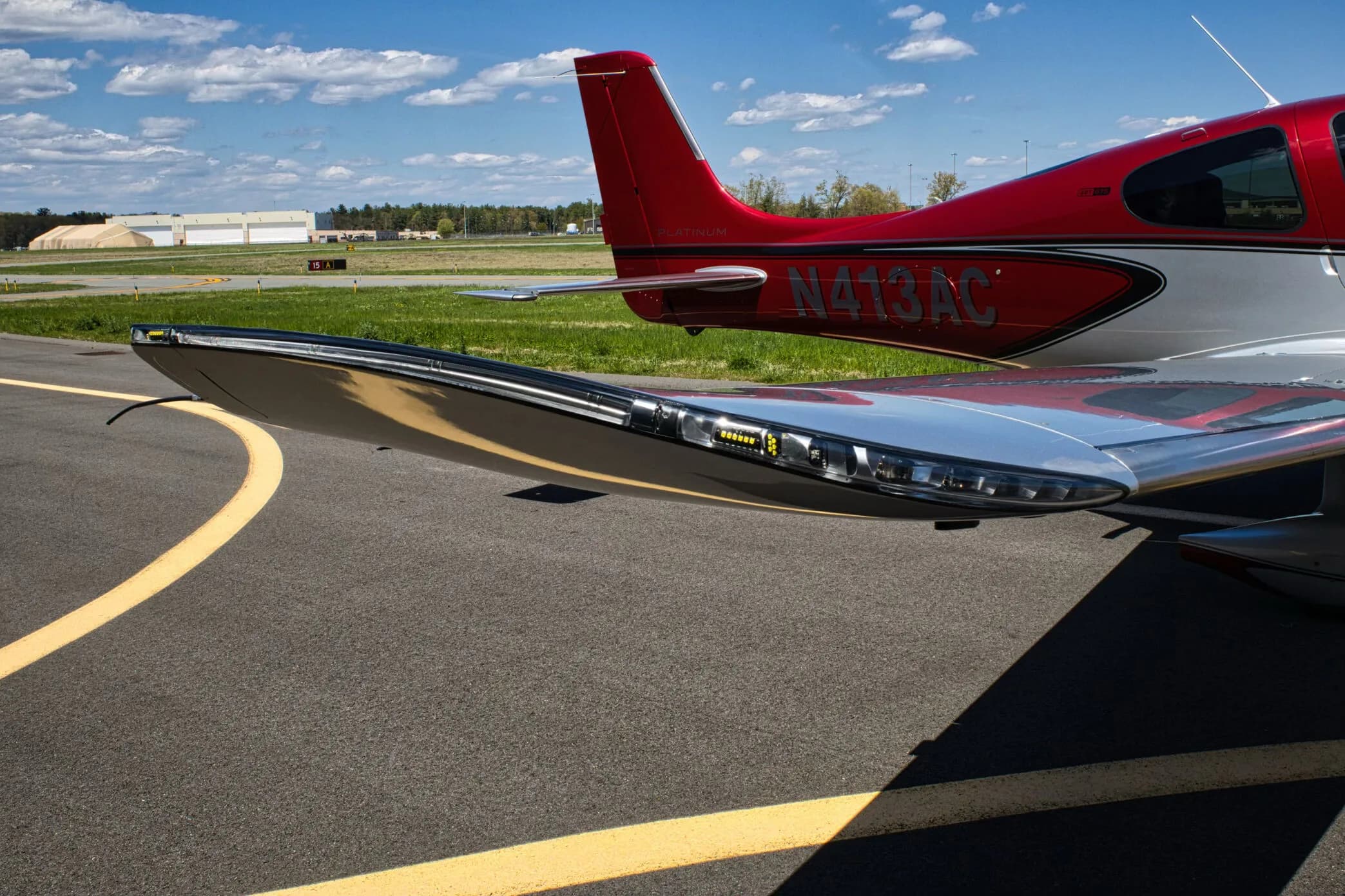 Close-up view of the right wingtip of the red and silver Cirrus SR22T aircraft, showing integrated lighting.