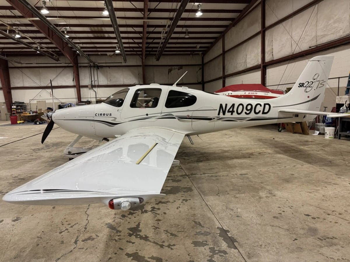 Side view of a Cirrus SR22T in a hangar, showing the registration number N409CD.