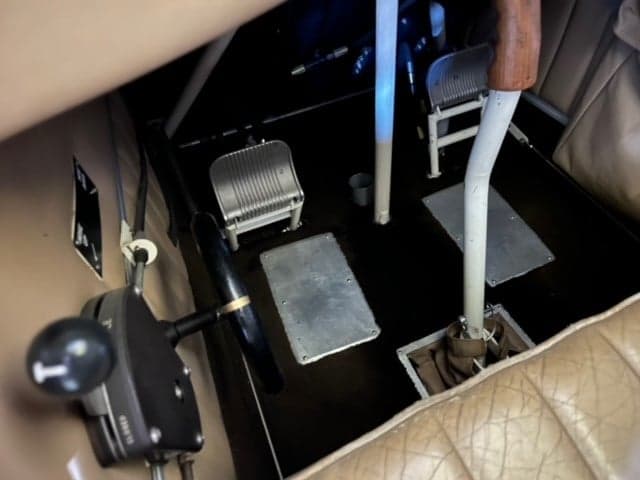 Interior view of the biplane's cockpit with tan leather seats and black seatbelts.