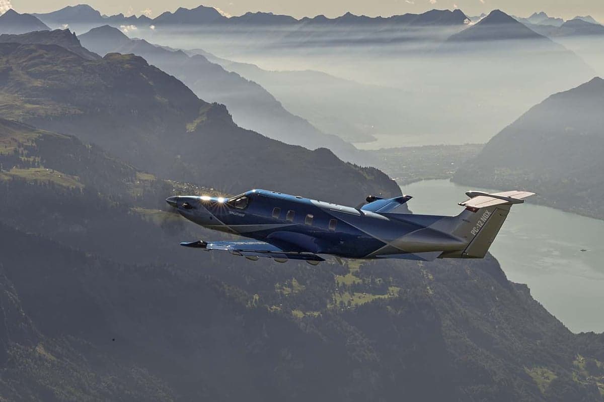 Pilatus PC-12 NGX in flight over a mountainous landscape.