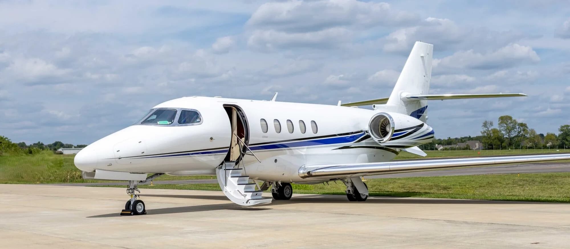 Side view of a white Hawker jet with the door open on the tarmac.