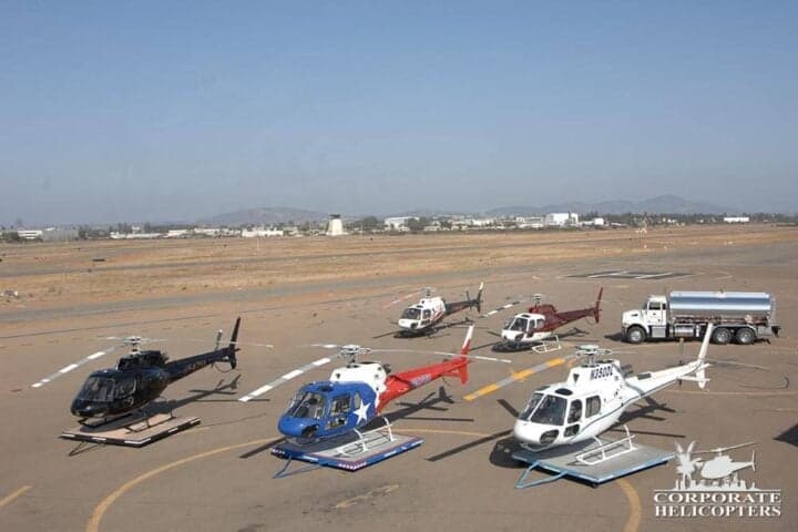 Several helicopters are lined up on a tarmac.